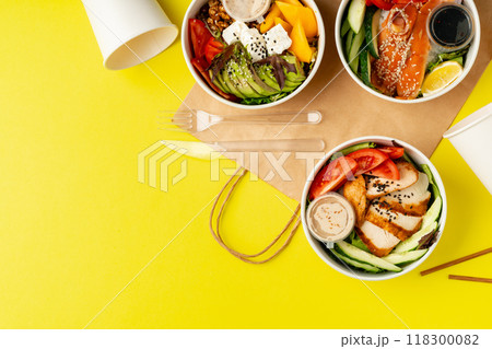 Top view of fresh poke bowls on yellow background 118300082