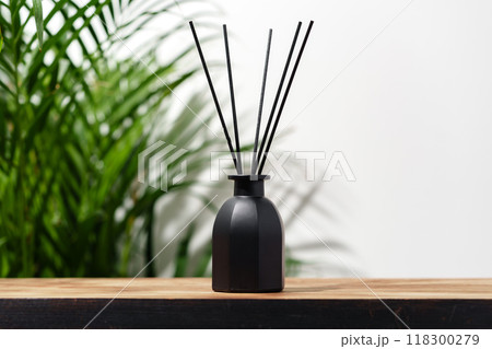 Black Reed Diffuser Bottle on Wooden Tabletop With Green Plant Black Reed Diffuser Bottle on Wooden Tabletop With Green Plant 118300279