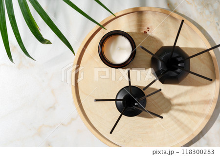 Black Reed Diffuser, Amber Candle, and Wooden Tray on White Surface 118300283