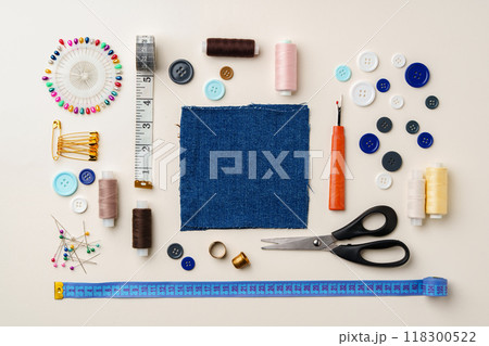 Sewing supplies and denim fabric arranged on a workspace for clothing alterations in a bright setting 118300522