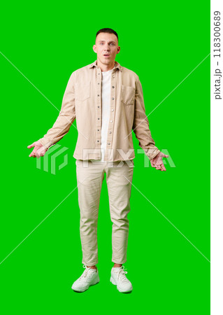 Confused Young Man Standing Against Bright Green Background With Open Arms in Uncertain Gesture Confused Young Man Standing Against Bright Green Background With Open Arms in Uncertain Gesture 118300689