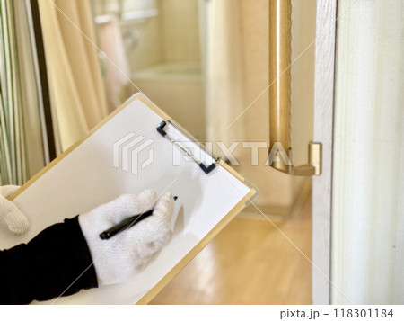 バスルームの前の手すりの前でクリップボードに記入する軍手をはめた手 バスルームの前の手すりの前でクリップボードに記入する軍手をはめた手 118301184