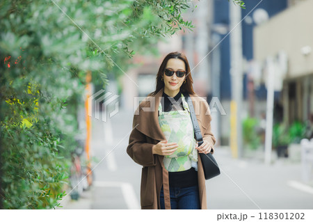 赤ちゃんを抱いて歩く母親　 118301202