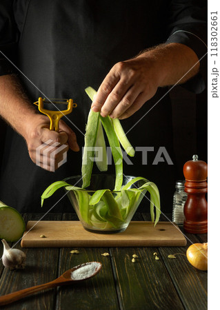 Chef prepares sliced zucchini before stir frying with vegetables in the kitchen. Vegetable marrow cooking concept for healthy vegetarian diet 118302661