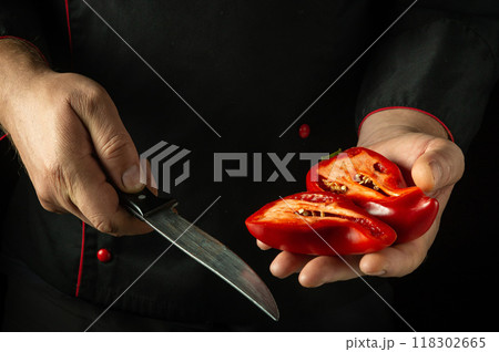 Presentation of bell pepper. Knife and red ripe pepper in the hands of a man. Low key concept of cooking a vegetarian dish Presentation of bell pepper. Knife and red ripe pepper in the hands of a man. Low key concept of cooking a vegetarian dish 118302665