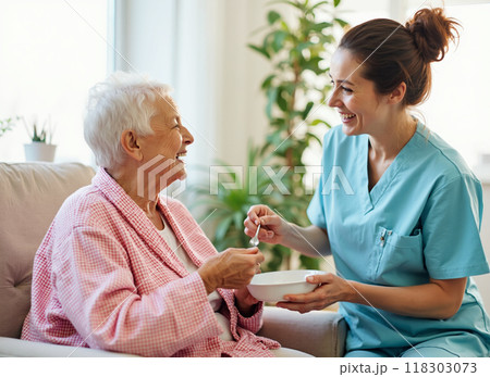 Nurse feeding elderly woman in a warm home setting Nurse feeding elderly woman in a warm home setting 118303073