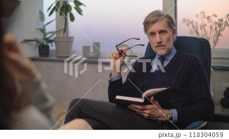 Mature psychotherapist listens to patient, asks questions during therapy 118304059
