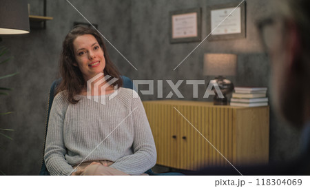 Adult woman sits in chair, discusses problems with psychologist, finds solution on counseling session Adult woman sits in chair, discusses problems with psychologist, finds solution on counseling session 118304069