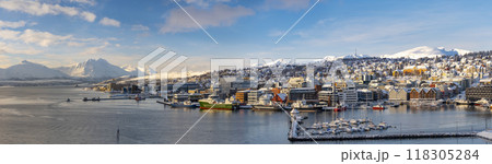 Panorama of norwegian city of Tromso in the winter. Snowy roofs, embankment near the port and fishing ships, Sunny winter day. 118305284