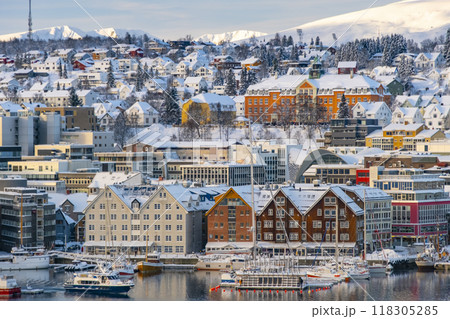 Norwegian city of Tromso in the winter. Snowy roofs, embankment near the port and fishing ships, Sunny winter day. 118305285