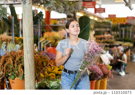 Young woman customer choosing bundle of limonium in open-air plants market Young woman customer choosing bundle of limonium in open-air plants market 118310873