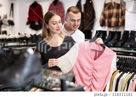 Man with wife participate in inspection of goods, help determine choice of blouse 118311181