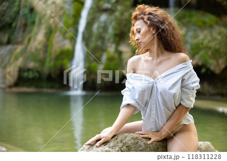 Erotic portrait of a half-naked woman with loose hair against the backdrop of tropical waterfall Erotic portrait of a half-naked woman with loose hair against the backdrop of tropical waterfall 118311228