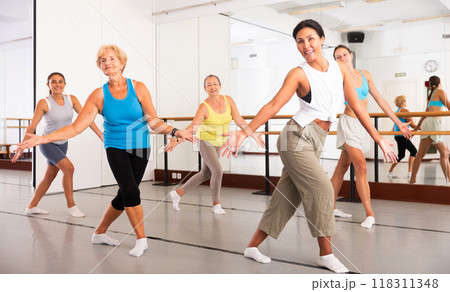 Group of active women practicing energetic dance in a studio 118311348