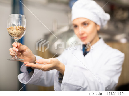 Female brewmaster holding glass of malt 118311464