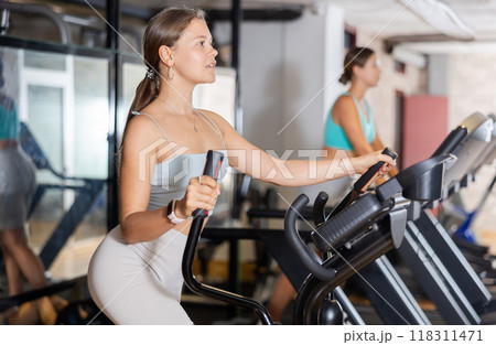 Young woman working out on elliptical machine 118311471