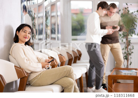 Young woman sitting in line with phone 118311668