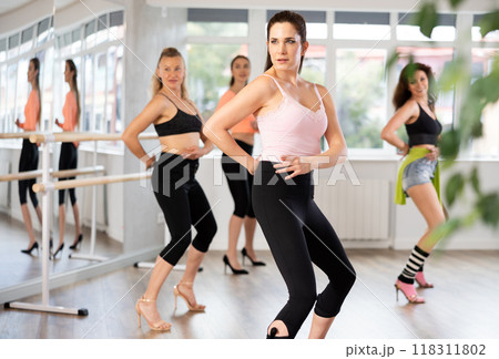 Female dancer practicing jazz-funk dance moves in high heels in studio 118311802