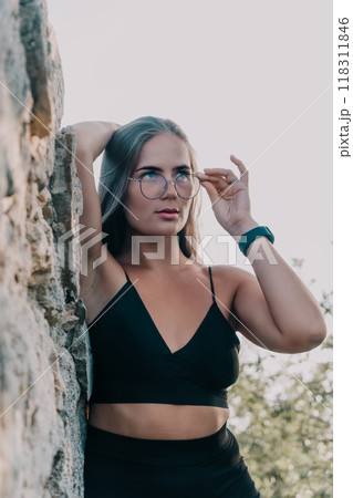 Woman Glasses Rock Portrait of a young woman wearing glasses and standing by a rock. Woman Glasses Rock Portrait of a young woman wearing glasses and standing by a rock. 118311846