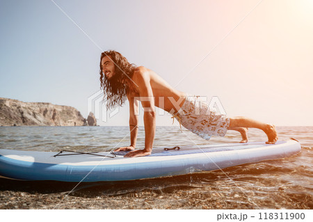man sup yoga. Happy sporty man practising yoga pilates on paddle sup surfboard. male stretching doing workout on sea water. Modern individual male hipster outdoor summer sport activity. 118311900