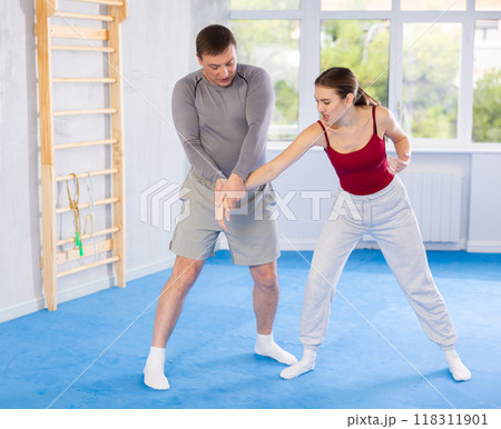 Young girl and middle-aged man practicing arm twist technique during self-defense courses Young girl and middle-aged man practicing arm twist technique during self-defense courses 118311901