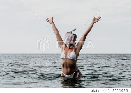 Woman Beach Ocean - A woman in a white bikini stands in the ocean with her arms raised. 118311926