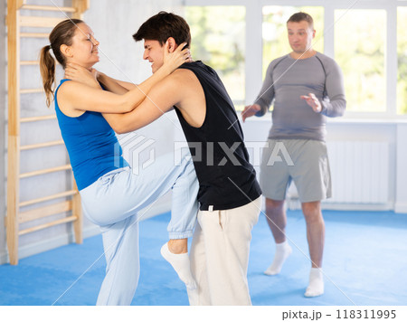 Guy and woman train to perform defense of strangling opponent, while learning self-defense 118311995