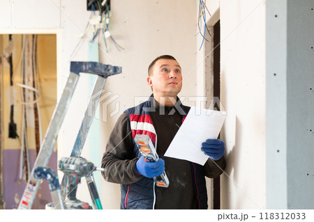 Electrician checking documentation during renovation works 118312033