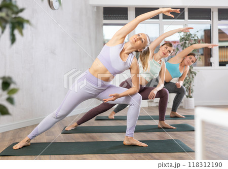 Young female yoga instructor giving pilates training session in wellness center 118312190