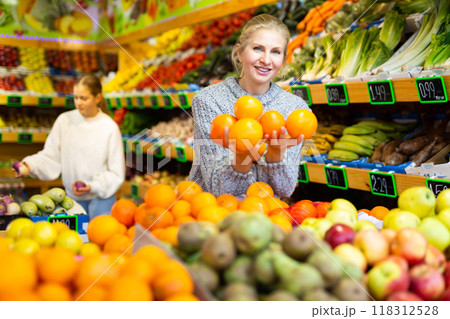 Young woman customer choosing fresh oranges on supermarket 118312528