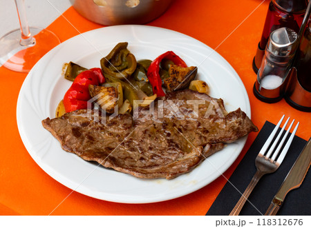 Delicious mediterranian style steak served with baked tomatoes and chili peppers Delicious mediterranian style steak served with baked tomatoes and chili peppers 118312676
