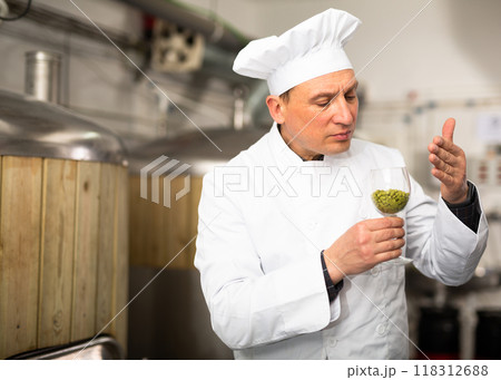 Focused brewer examining smell of granulated hops in glass Focused brewer examining smell of granulated hops in glass 118312688