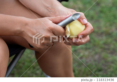 Women's hands peel potatoes with a knife, close-up 118313436