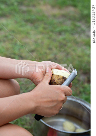 Women's hands peel potatoes with a knife, close-up 118313437