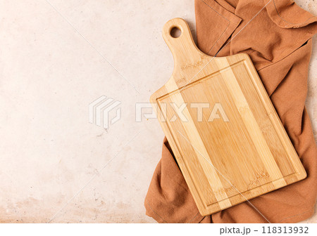 Cutting board, beige, unpainted, with a kitchen towel, on a beige background, top view, 118313932
