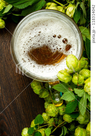 A mug of beer , on a wooden table, with a branch of fresh hops, rustic , no people, A mug of beer , on a wooden table, with a branch of fresh hops, rustic , no people, 118314042