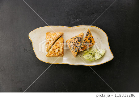 Freshly baked artisan bread slices with almonds and seeds, served with herbed butter on a plate 118315296