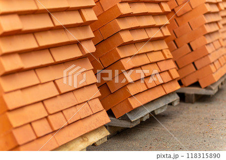 Stacks of new, red ceramic brick stacked on wooden pallets. 118315890