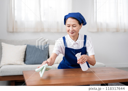 青色のエプロンを付けた白いポロシャツのシニア女性のハウスキーパー 118317644
