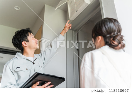 分電盤・ブレーカーの説明をする作業員の男性と説明を聞く主婦 分電盤・ブレーカーの説明をする作業員の男性と説明を聞く主婦 118318697