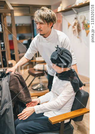 ブランケットを取り、椅子を回転してシャンプー台にお客様を誘導する美容師 118320158