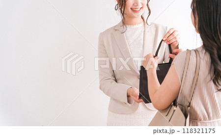高級店で紙袋・商品を渡すショップ店員・販売員と買い物客の女性（デパート・百貨店・ブランド品） 118321175