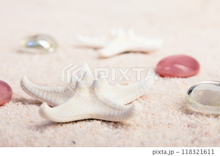White sea stars and red glass pebbles on the sand. 118321611