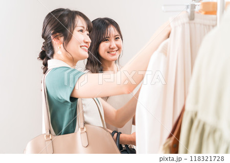 アパレルショップ・洋服屋で鏡で洋服を合わせる買い物客の女性・女友達・ショッピング アパレルショップ・洋服屋で鏡で洋服を合わせる買い物客の女性・女友達・ショッピング 118321728