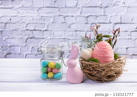 Easter nest with eggs and branches, bunny and jar with candies. 118321777