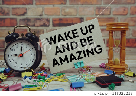 Wake Up And Be Amazing text on paper card with alarm clock and stationary on wooden background Wake Up And Be Amazing text on paper card with alarm clock and stationary on wooden background 118323213