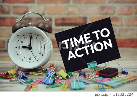 Time to Action text on paper card with alarm clock and stationary on wooden background 118323224