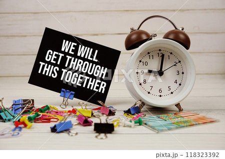 We Will Get Through This Together text on paper card with alarm clock and stationary on wooden background 118323392