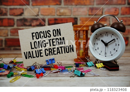 Focus On Long-term Value Creation text on paper card with alarm clock and stationary on wooden background 118323408