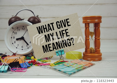 What Gives My Life Meaning? text on paper card with alarm clock and stationary on wooden background 118323443